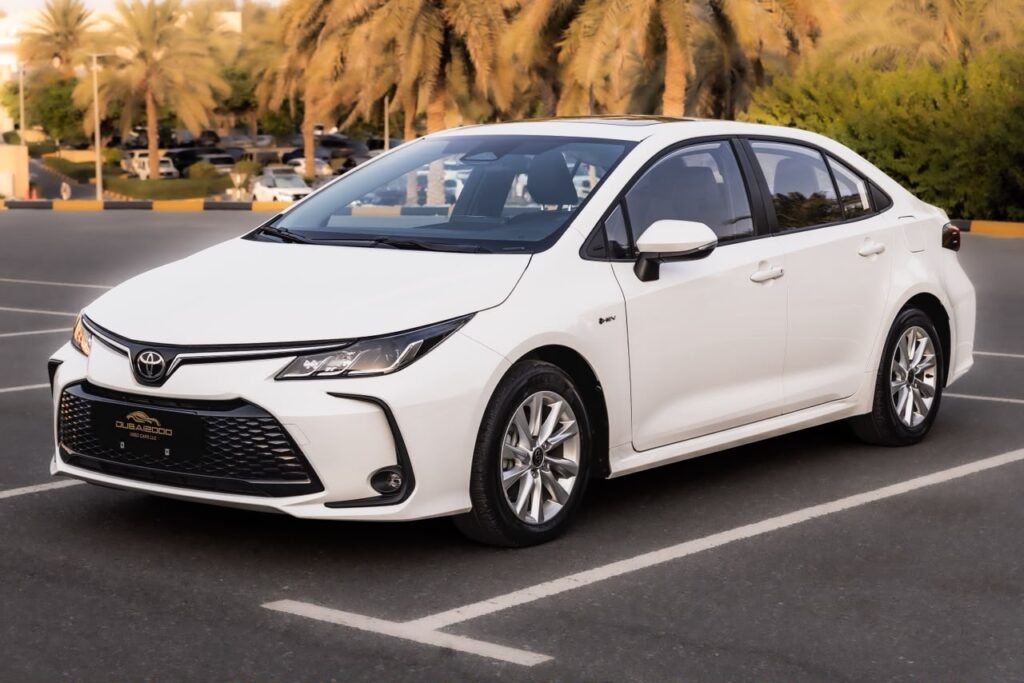 White Toyota sedan parked in a lot with palm trees in the background; front left angle view.