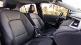 Front interior of a car showing dark leather seats, center console, and steering wheel with a panoramic sunroof above.