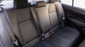 Black leather rear car seat with three-seat belts and headrests, viewed from the passenger side window area