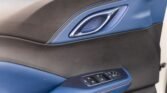 Interior car door panel with blue and black materials and a window control console with multiple buttons and a circular control pad
