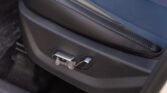 Close-up of a car seat base showing side adjustment controls on a dark panel near blue perforated upholstery.