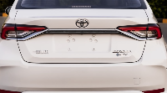 Rear view of a white Toyota sedan (Camry), parked outdoors, displaying the taillights, logo, and trunk lid.